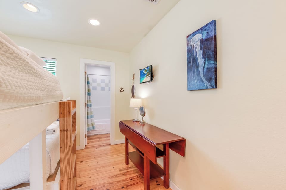 Your cozy bedroom nook features warm wood floors, nautical art, and a handy workspace desk perfect for morning coffee or evening planning.