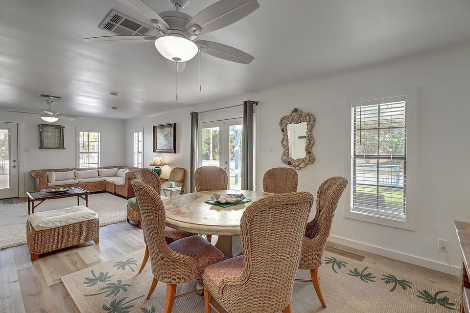 Gather around your spacious dining table where wicker chairs and tropical touches create a breezy coastal vibe, perfect for morning coffee or evening meals.