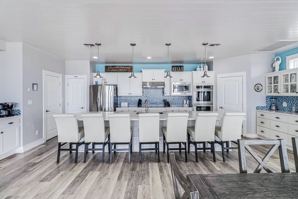 Your dream kitchen awaits with a spacious island for eight, gleaming appliances, and coastal blue accents that create the perfect gathering spot for your group.