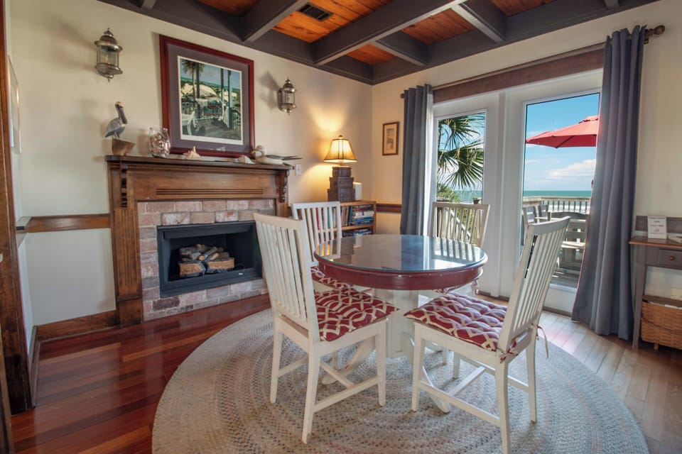 Gather around your dining table with stunning ocean views just beyond your private balcony. The warm wood ceiling and cozy fireplace create an inviting retreat after beach days.