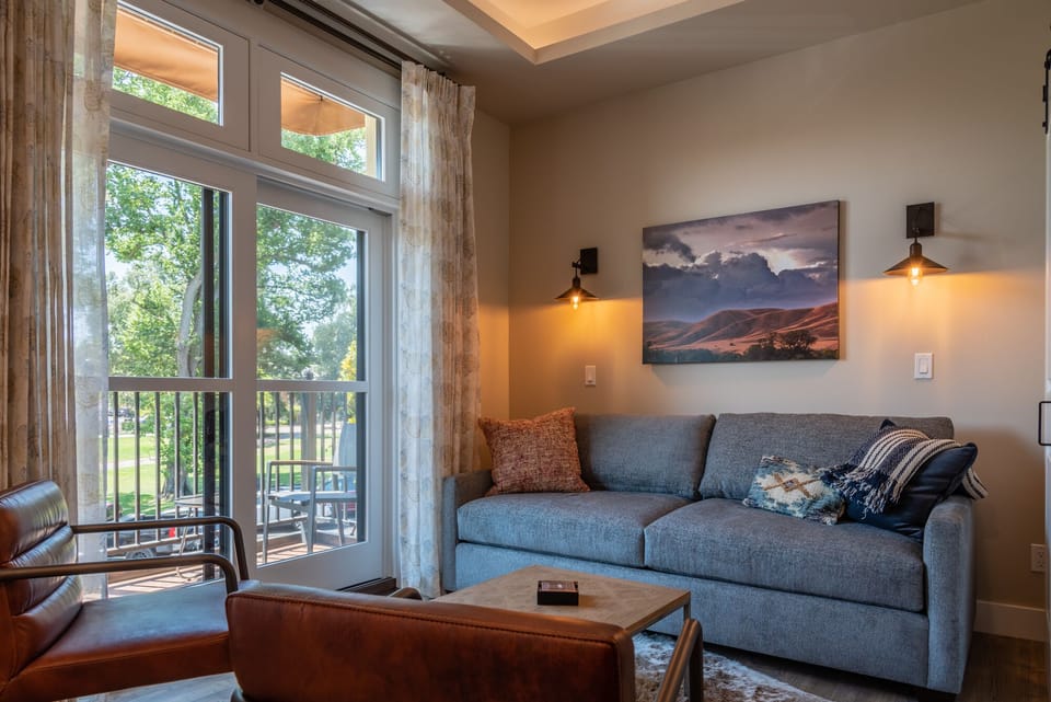 A gray sofa and glass doors keep the living area bright and relaxed.