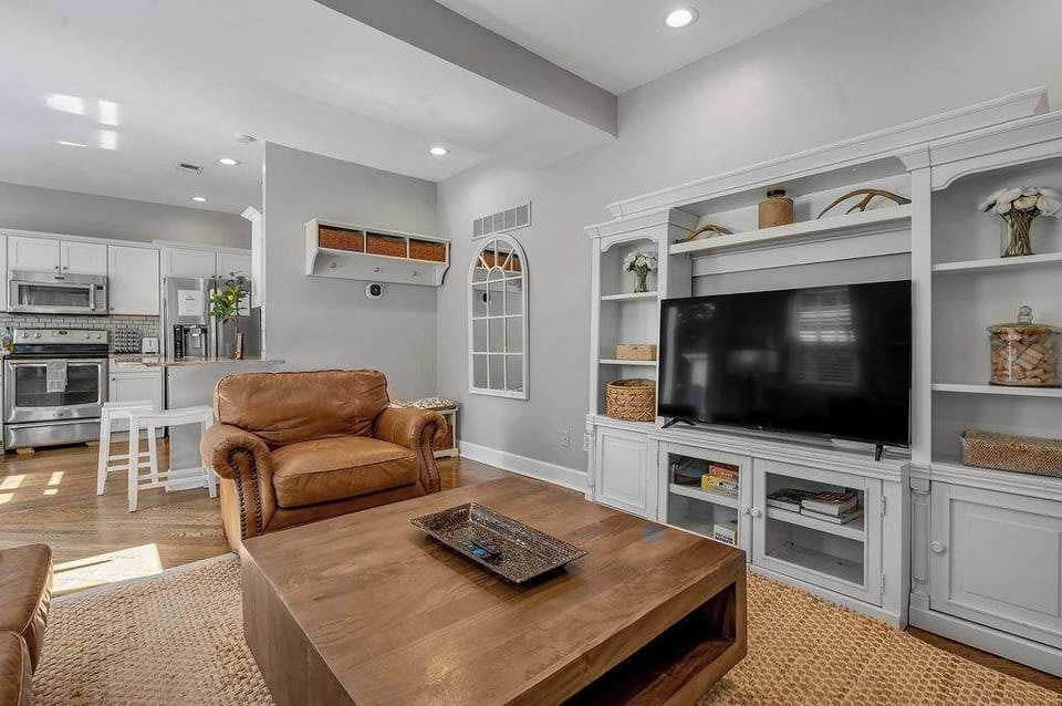 Living area with a leather armchair, built-in shelving and a large smart TV.