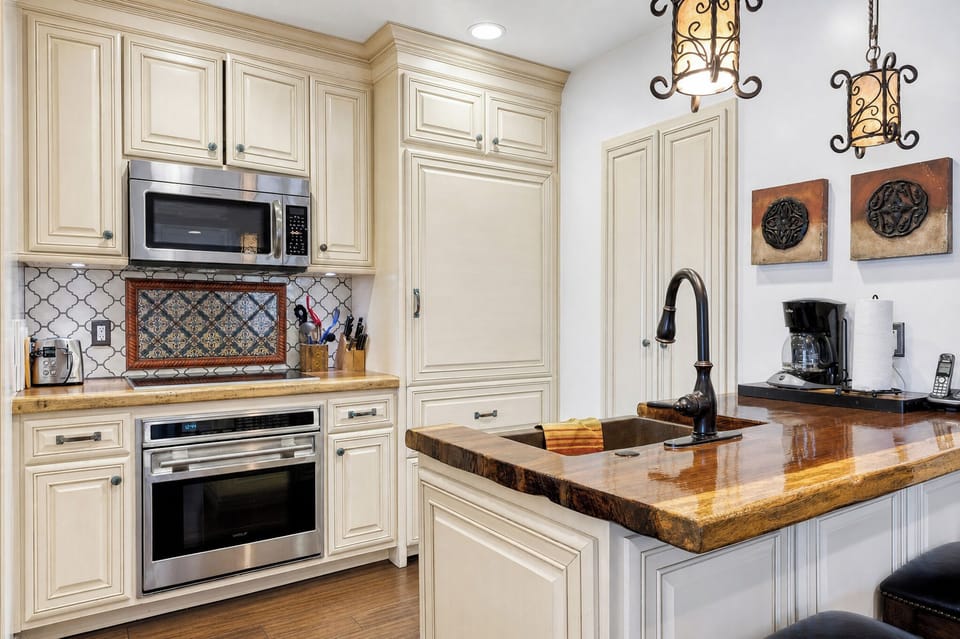 This elegant kitchen blends classic charm with modern convenience—cream cabinetry, stunning wood countertops, and stainless appliances await your culinary creations.
