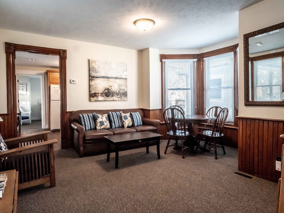 Family Room with leather sofa, arm chair and ottoman and a table w/ four chairs.