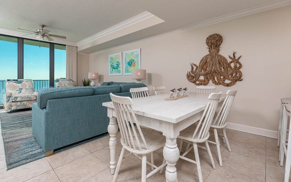 Gather around the dining table, surrounded by coastal decor and inviting seating, perfect for meals and conversation