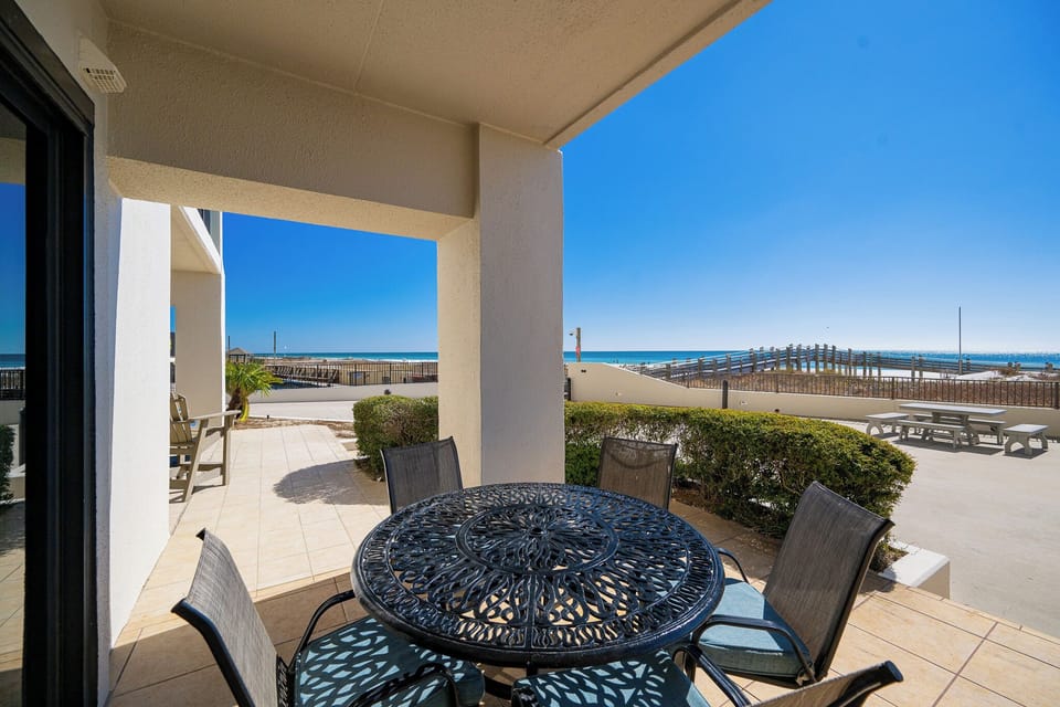 Metal patio table shadows play over your tiled balcony where you watch waves meet the coast