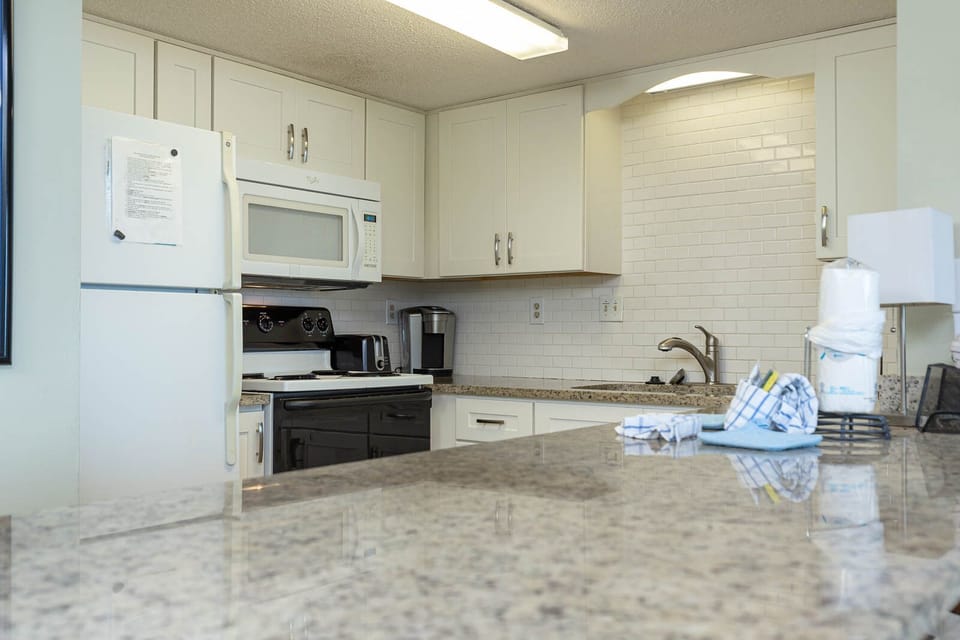 This kitchen features sleek white cabinetry, granite countertops, and modern appliances for a delightful cooking experience