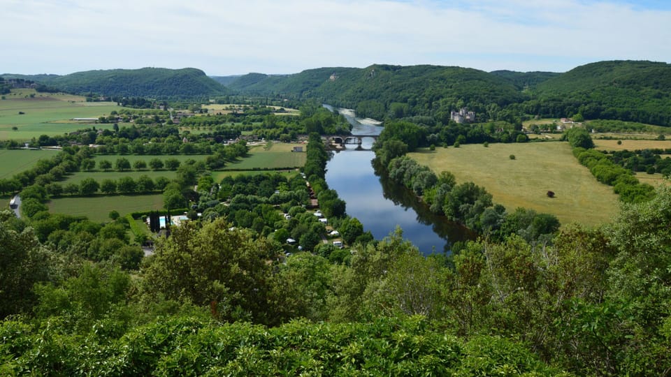 Wide river winding through a green valley of fields and woodland viewed from an elevated position