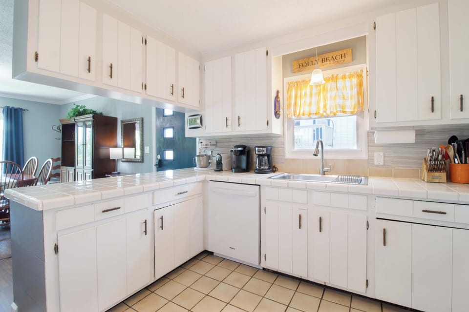 Your bright, fully-equipped kitchen invites you to brew morning coffee while sunlight streams through the cheerful Folly Beach window. White cabinetry and ample counter space make meal prep feel effortless and relaxed.