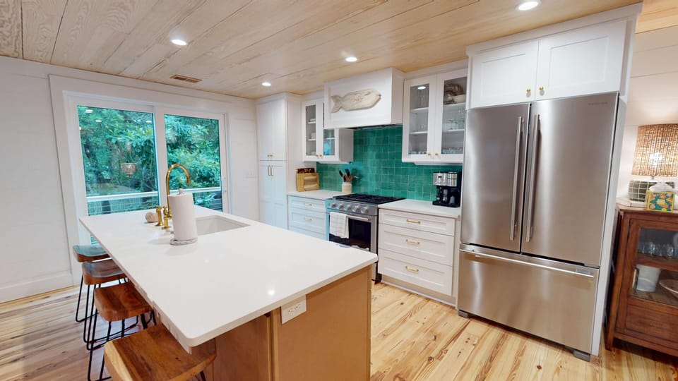 Step into a bright, modern kitchen where turquoise tile backsplash pops against white cabinetry. Your meals practically cook themselves with stainless appliances and a spacious island perfect for gathering with loved ones.