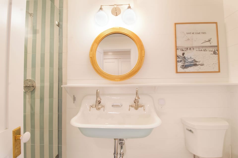 Your private bathroom features a vintage-inspired sink, fresh white shiplap walls, and cheerful coastal details that set the perfect beach-house tone.