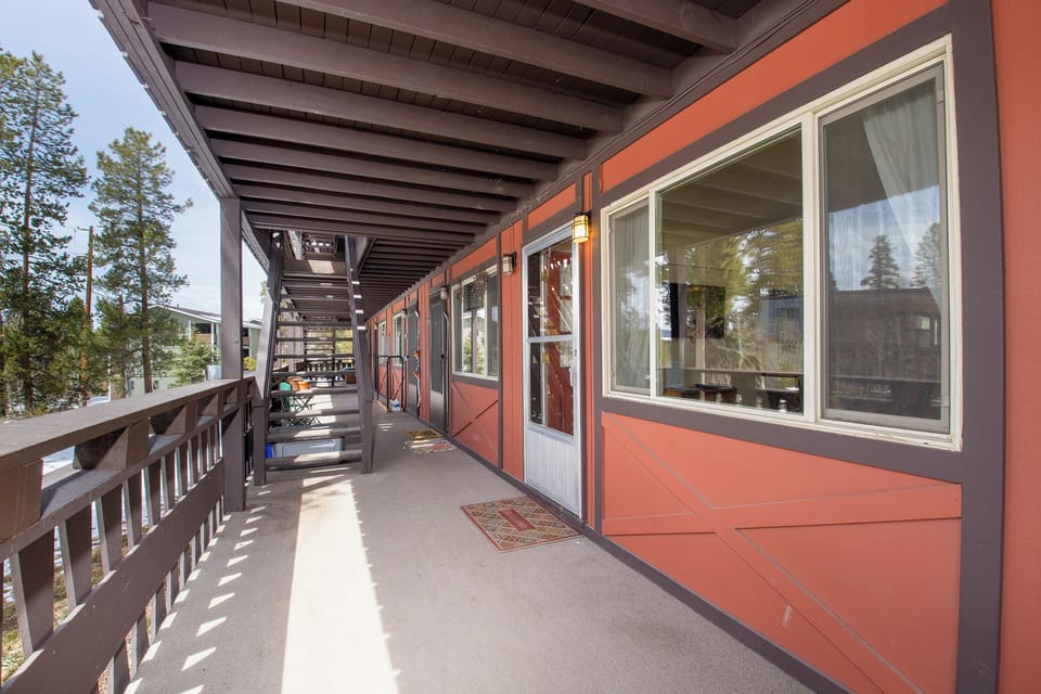 Spacious covered balcony with rustic charm, featuring exposed wooden beams and forest views for your mountain retreat experience.