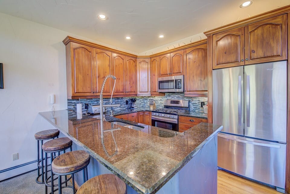 5 burner gas stove, granite, stainless steel and seating for 4 at the bar.