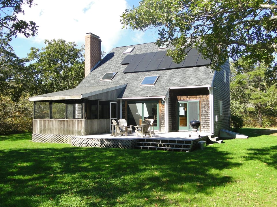 Rear porch and deck. Charcoal grill. Solar panels on roof. 