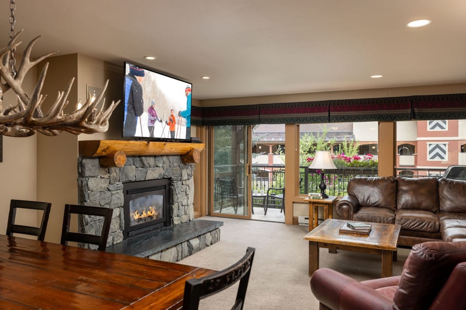 Unwind by the fireplace in this warm space with leather seating, mountain-inspired decor, and balcony access to fresh air and village charm.