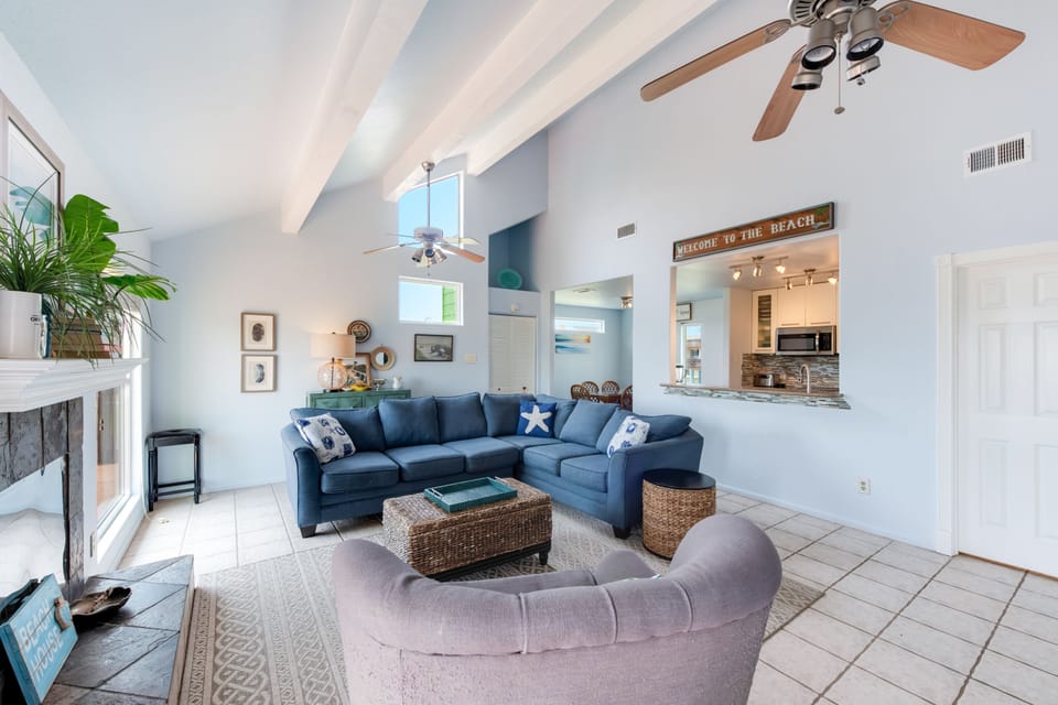 Sink into the plush sectional sofa beneath vaulted ceilings where coastal charm meets comfort in your beach-themed retreat.