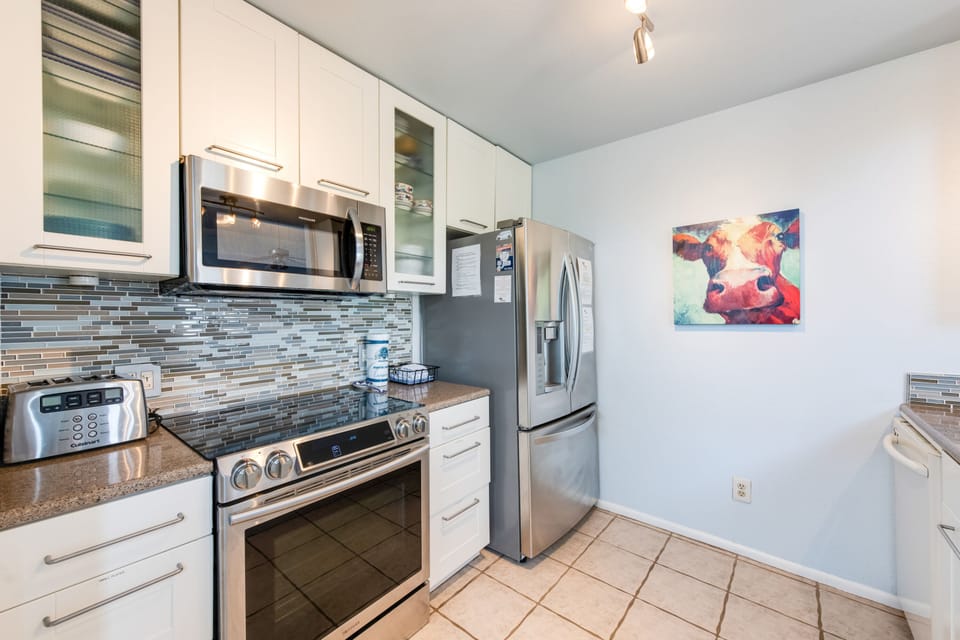 Prepare your favorite meals in this sleek, fully-equipped kitchen featuring modern stainless steel appliances and stylish tile backsplash.
