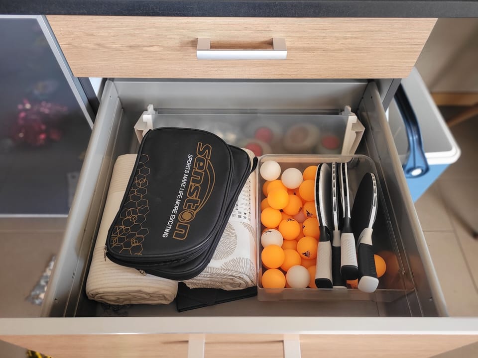 The table tennis bats and balls are stored in a drawer next to the dining table 