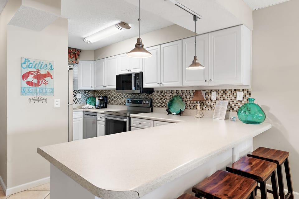 Your fully equipped kitchen invites you to whip up meals with ease—complete with sleek appliances, coastal decor accents, and a breakfast bar perfect for morning coffee or casual dining.