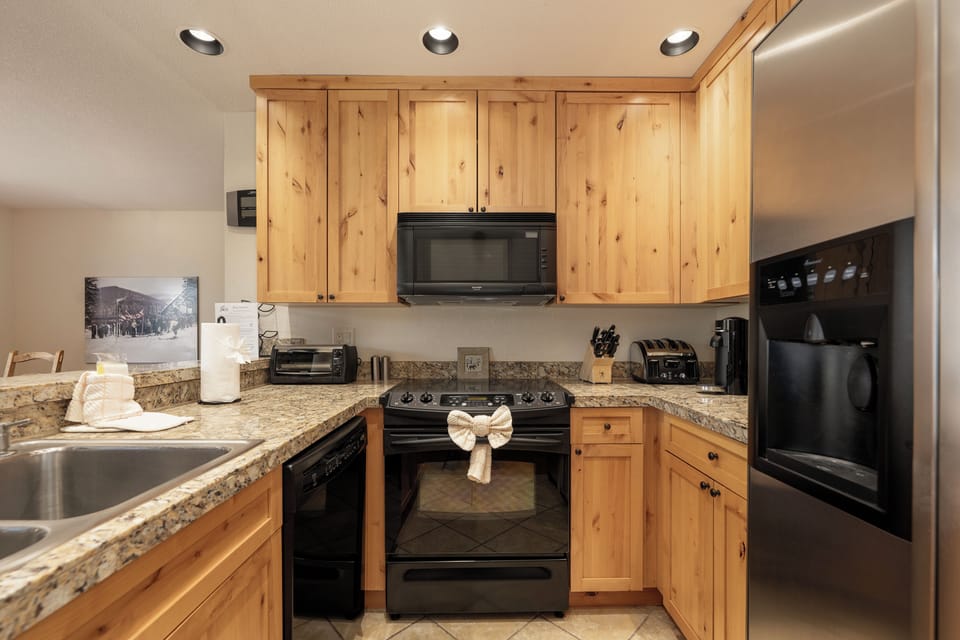 Your fully equipped kitchen features warm wood cabinets, granite countertops, and modern appliances for preparing memorable meals during your stay.