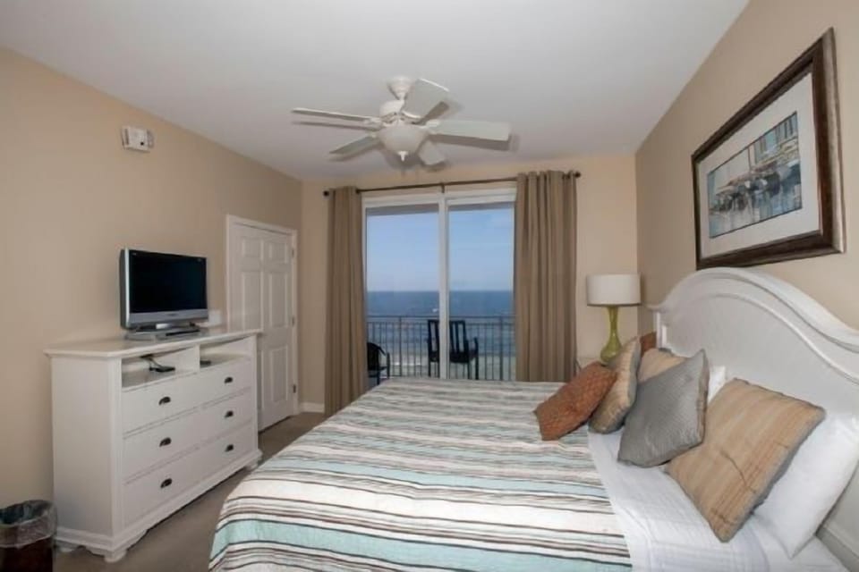 The master bedroom with a king-sized bed and a sliding door to the balcony