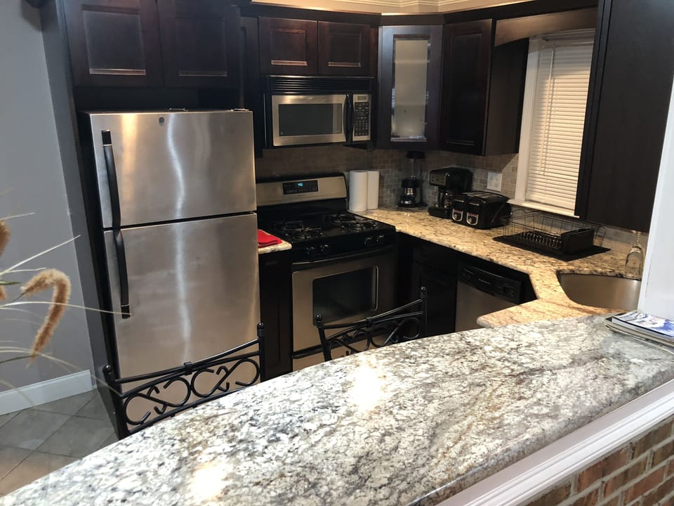 Beautiful marble granite counter top and lovely rich dark wood cabinets.