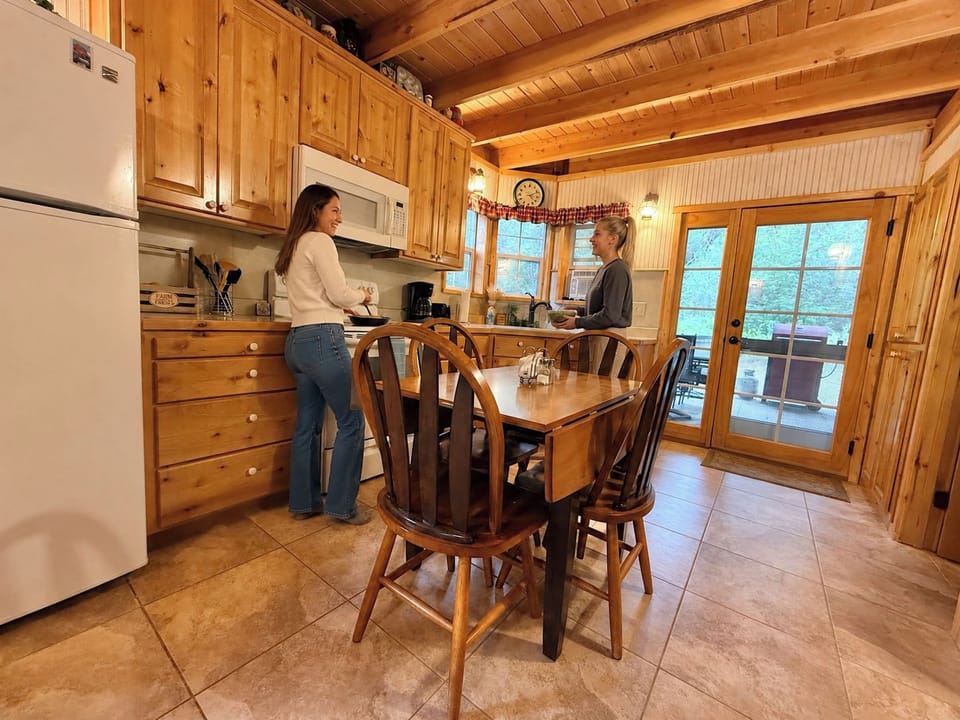 Rustic log cabin kitchen with wood dining table, perfect for gathering after a day on the 50-acre ranch.