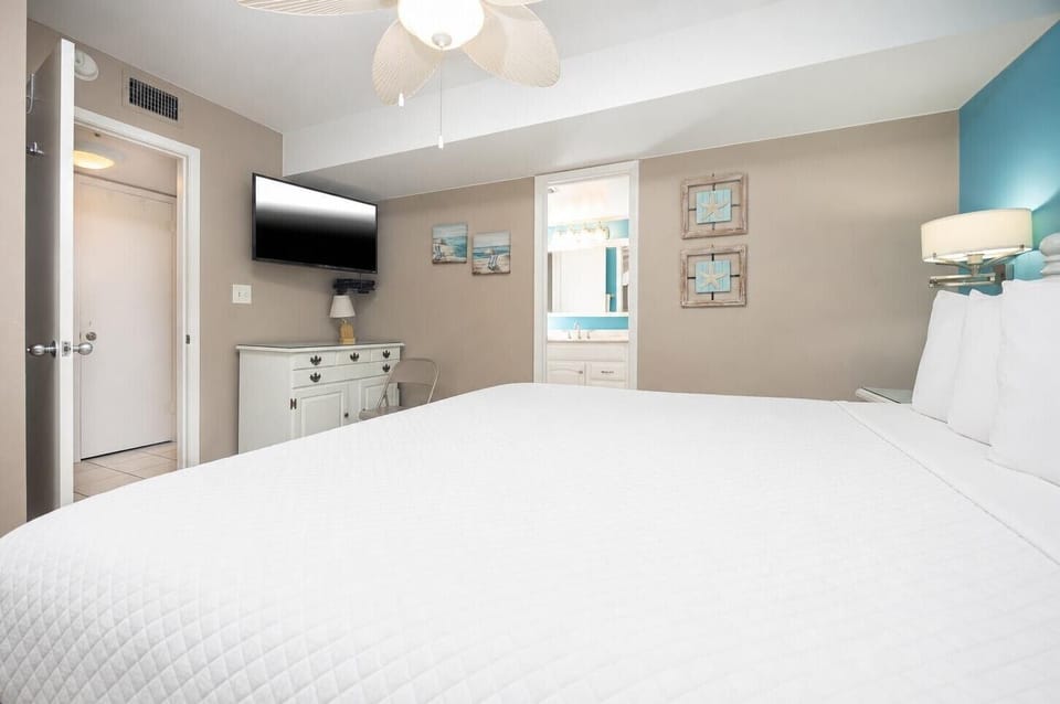 The bedroom featuring a plush king bed, flat-screen TV, and beach-themed decor for a relaxing getaway experience