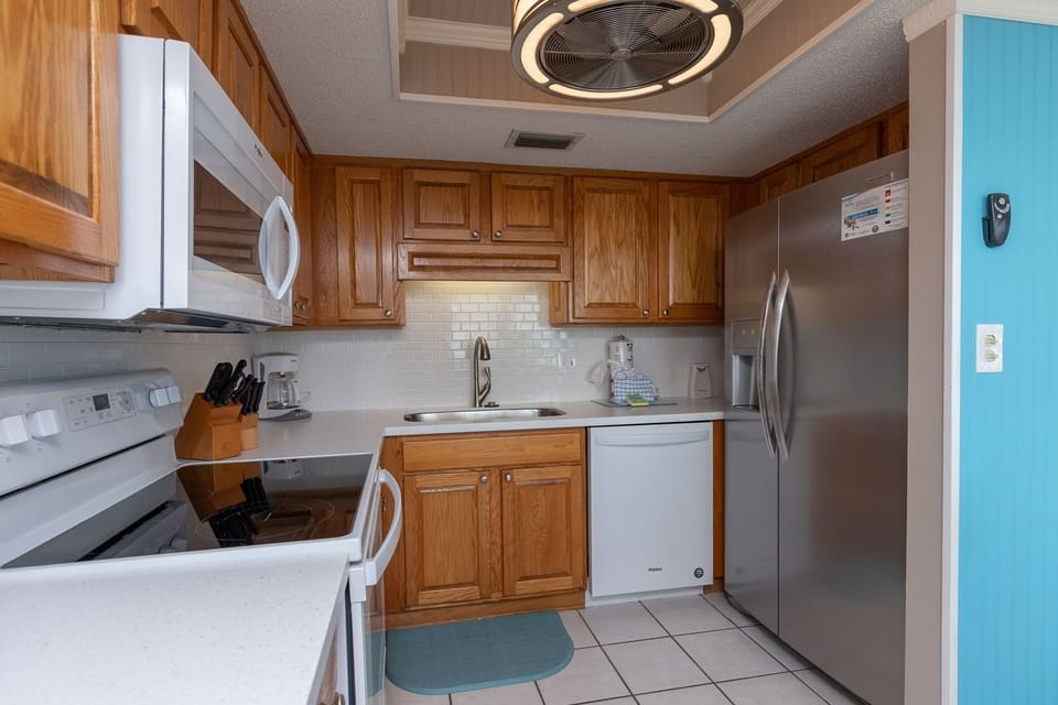 Essential kitchen featuring white and stainless appliances, wooden cabinets, coffee maker, and a cozy blue accent wall