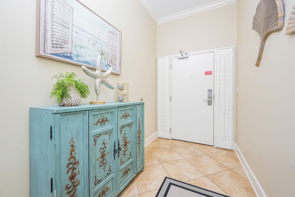 This welcoming entryway features a charming cabinet, coastal decor, and a beautiful wall art piece, setting a relaxing tone