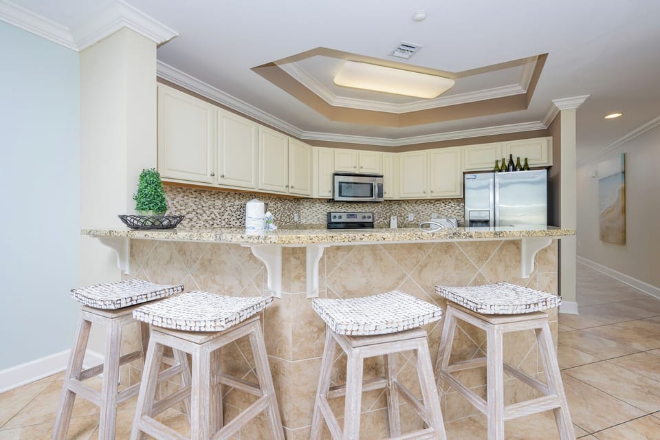 This kitchen features granite countertops, stainless appliances, and a cozy bar area with stylish stools for relaxed dining