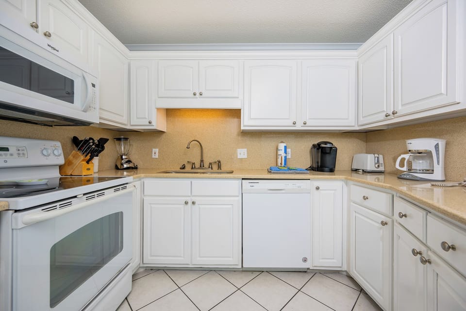 White cabinetry complements the countertops in this kitchen that includes a Keurig and coffee maker for the perfect brew