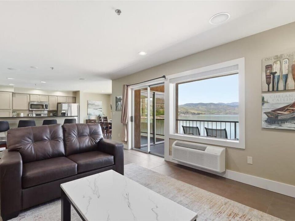 Relax in this inviting living room where expansive windows frame stunning lake and mountain views—your perfect retreat to unwind and enjoy the scenery.