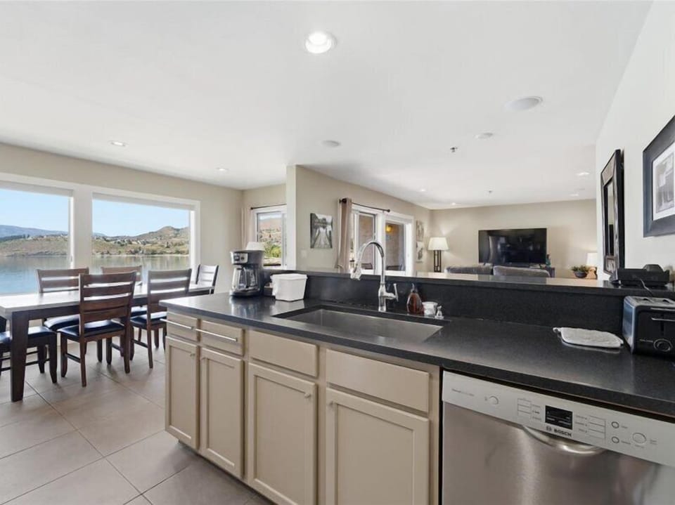 Step into your open-concept kitchen and living space where stunning lake views greet you through expansive windows. Prepare meals with modern appliances while staying connected to your group gathered nearby.