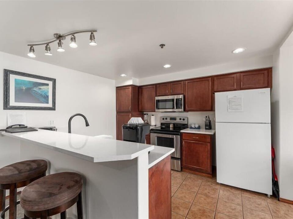 Your fully equipped kitchen awaits with rich cherry cabinets, modern appliances, and a breakfast bar perfect for morning coffee.