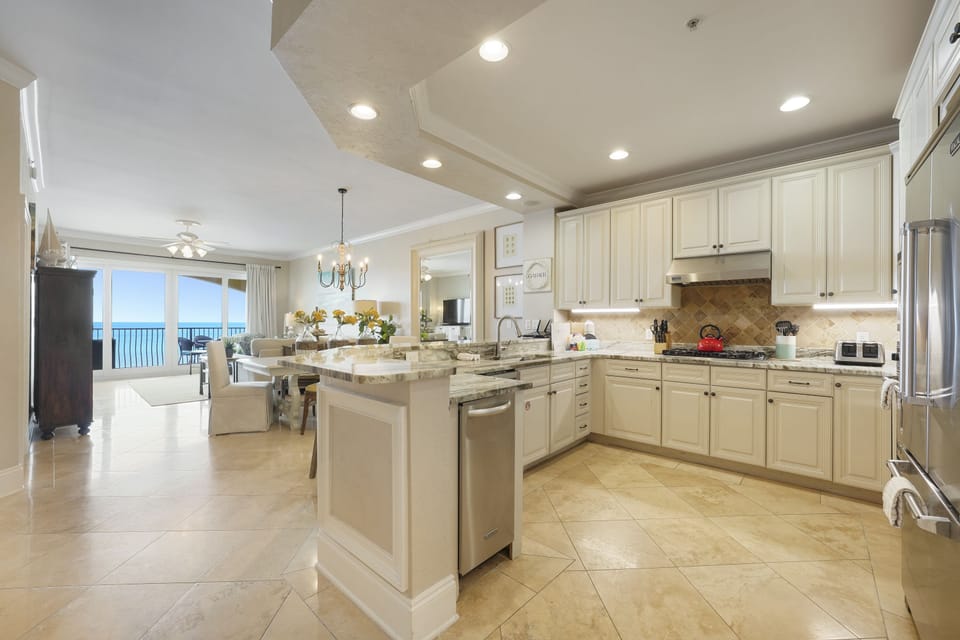 Elegant coastal style kitchen with oversized island and bar seating, granite countertops, and high end Viking appliances where you can cook delicious meals and dine while overlooking the Gulf!