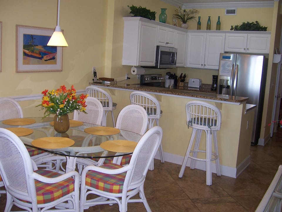 Dining Area with Table that Seats Six and Three Bar Stools Looking Into Kitchen 