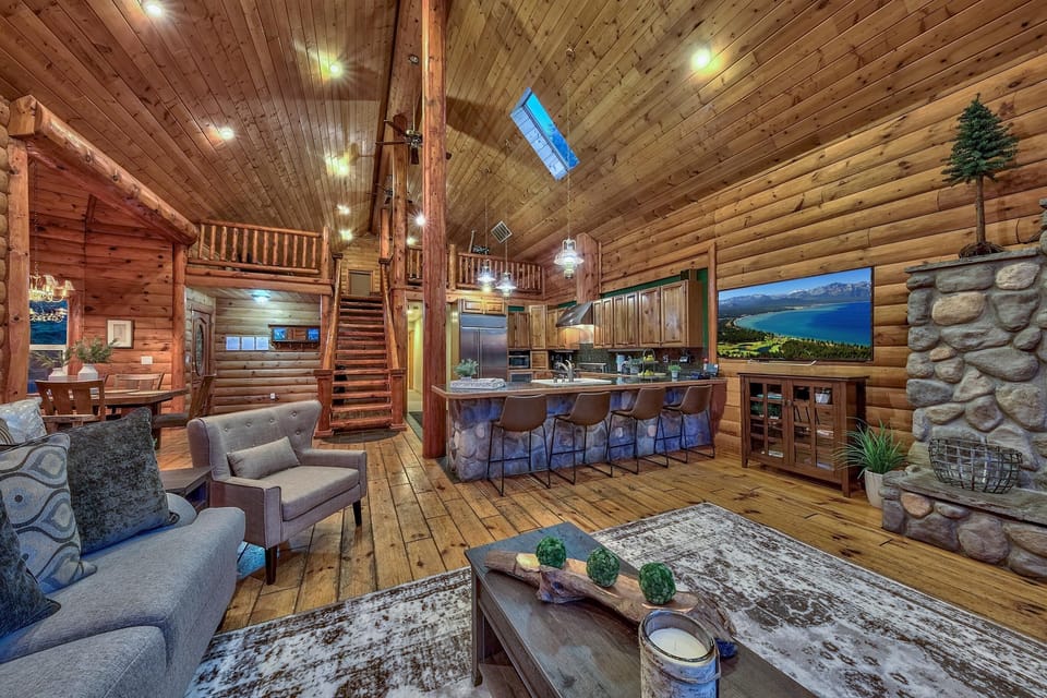 Open living area features knotty pine walls, vaulted ceiling with skylight, stone kitchen island, and a stone fireplace.