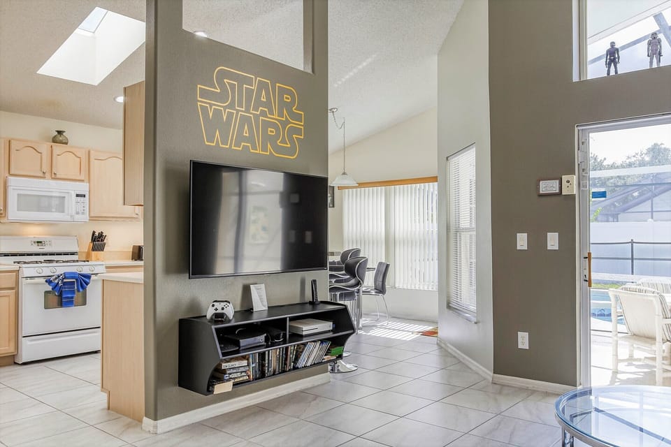 Wall-mounted, flat screen TV with Xbox One and video library.