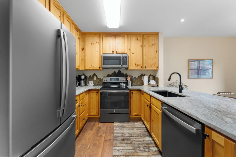 Your fully-equipped kitchen awaits with warm wood cabinets, granite counters, and modern appliances for preparing delicious meals during your stay.