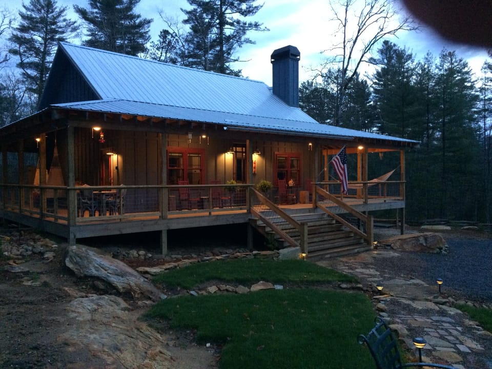 Dusk at Stone-Hinge cabin features
wraparound porch with lighted ceiling fans 
