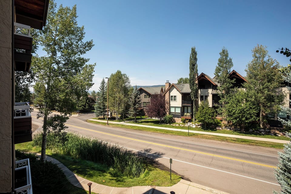 Tree-lined residential street with well-maintained homes and mountain backdrop creates a peaceful neighborhood setting.