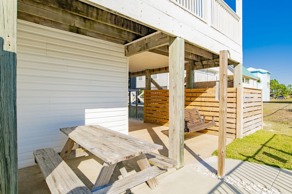 view is back side of house, porch swing, picnic table, charcoal grill on right