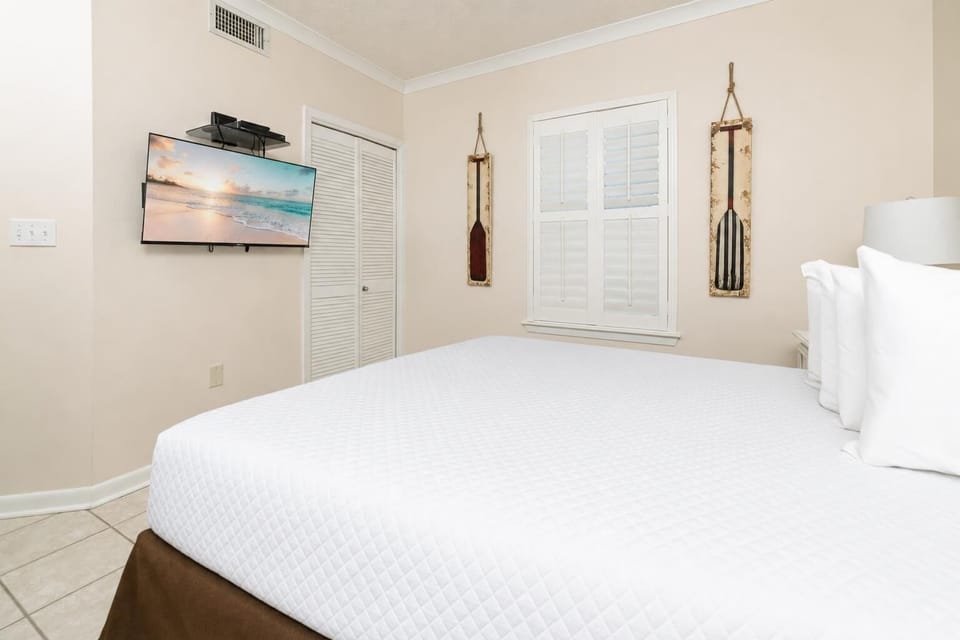 Relax in this inviting guest bedroom featuring a queen bed, a TV for entertainment, and charming coastal decor