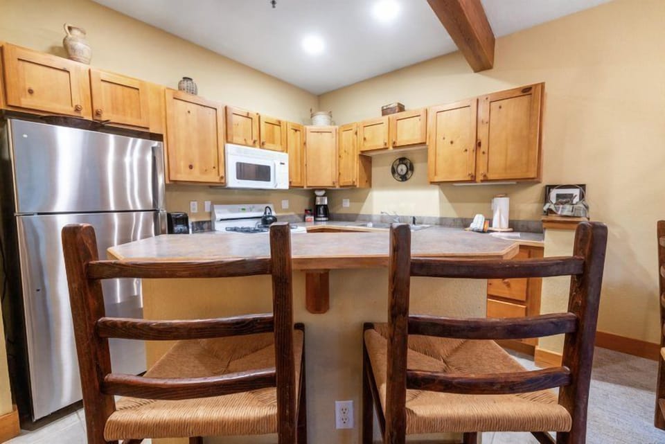The kitchen island with rustic stools offers a communal space for enjoying snacks or chatting while cooking.