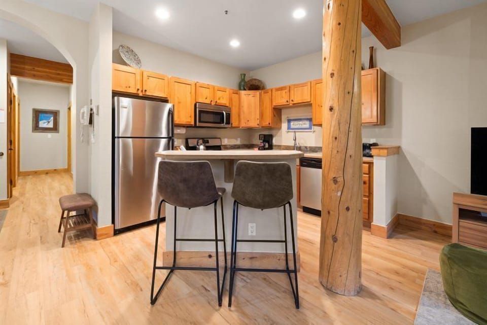 The cozy dining area seamlessly connects to the kitchen, offering convenient bar seating that enhances the condo's rustic charm.