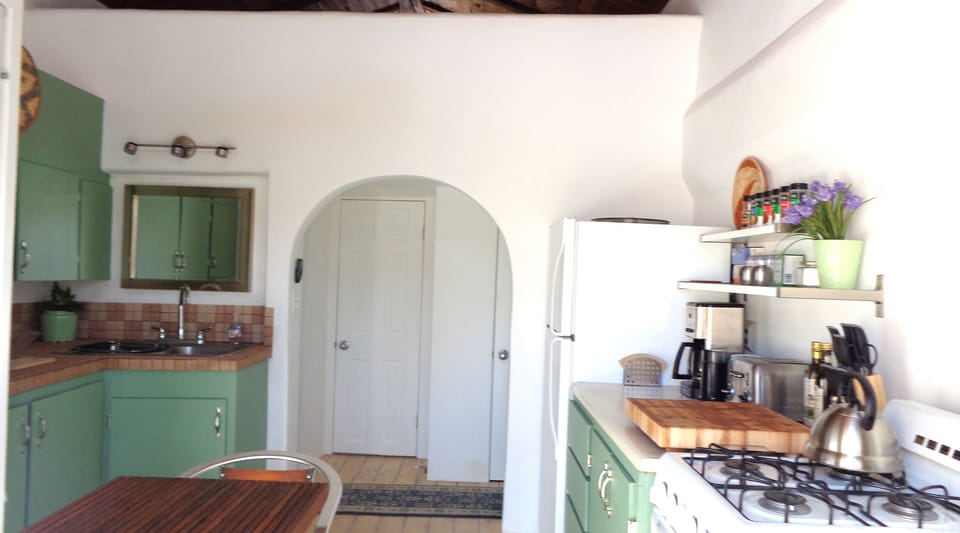 Kitchen view from french doors, bathroom door behind archway in background