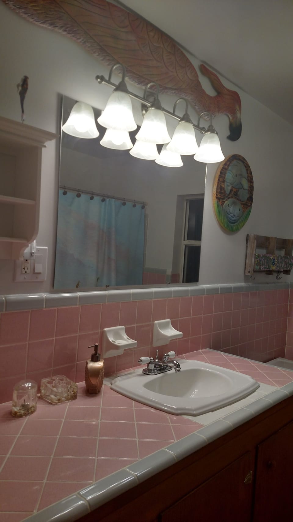 Main bathroom restored to its 50's pink and grey tile, deep tub, fun artwork.