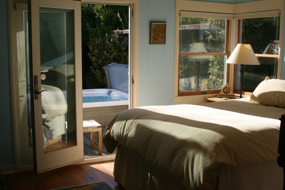Sunny Master bedroom with queen bed that opens up to wood deck and spa