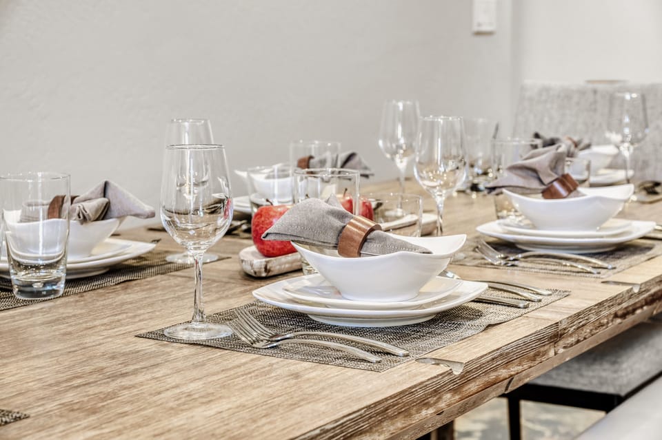 Gather around this beautifully set dining table where elegant place settings and sparkling glassware await your memorable meals together.